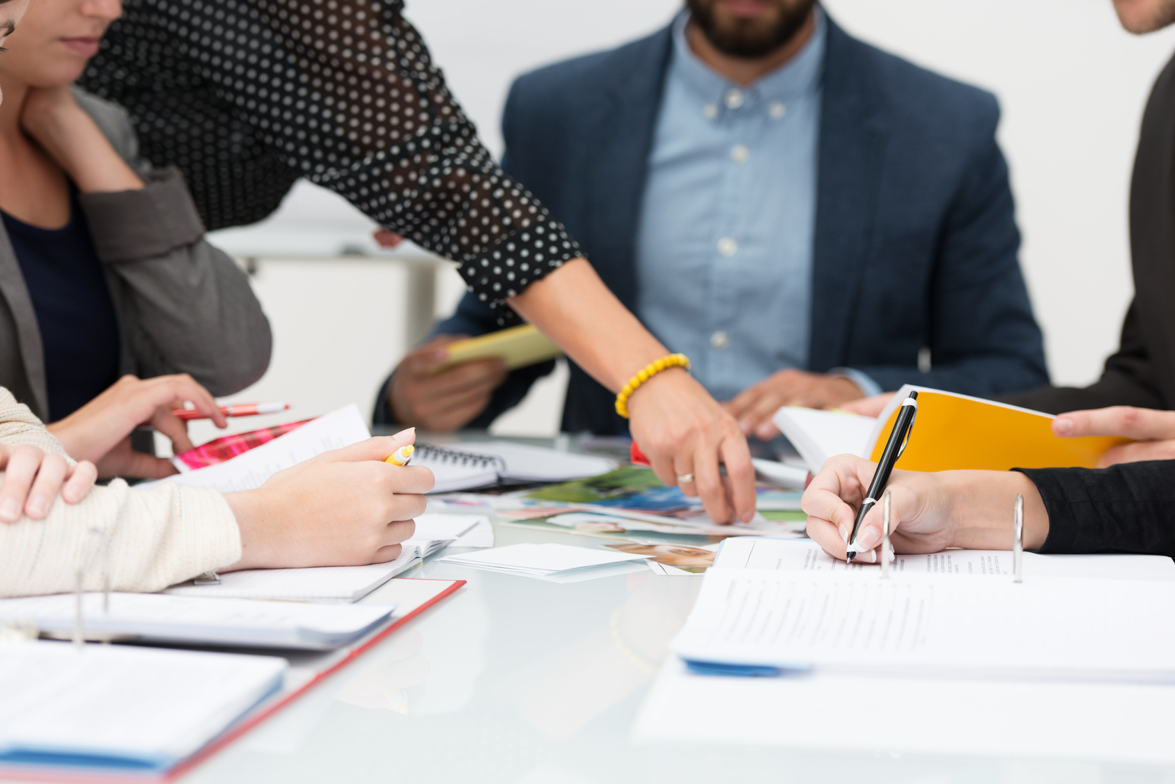 Gruppenbesprechung Gruppe von Personen, die in einer Besprechung zusammenarbeiten, diskutieren und Notizen mit Dokumenten und Notizbüchern auf einem Tisch schreiben.