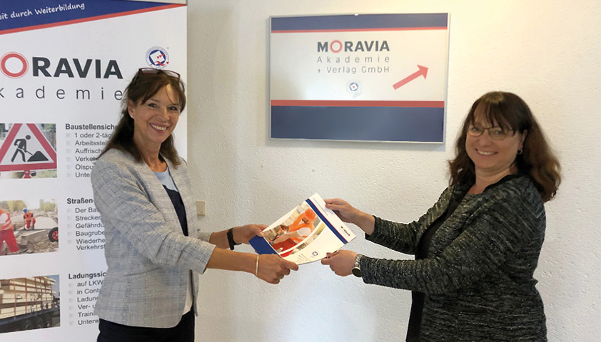 Frau Dürer und Frau Hallberg halten gemeinsam den Katalog von 2022