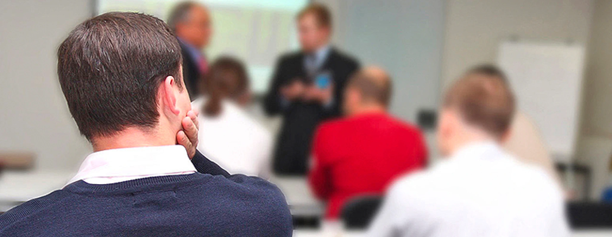 Seminarteilnehmer mit verschwommener Sicht auf andere Teilnehmer und Seminarleiter