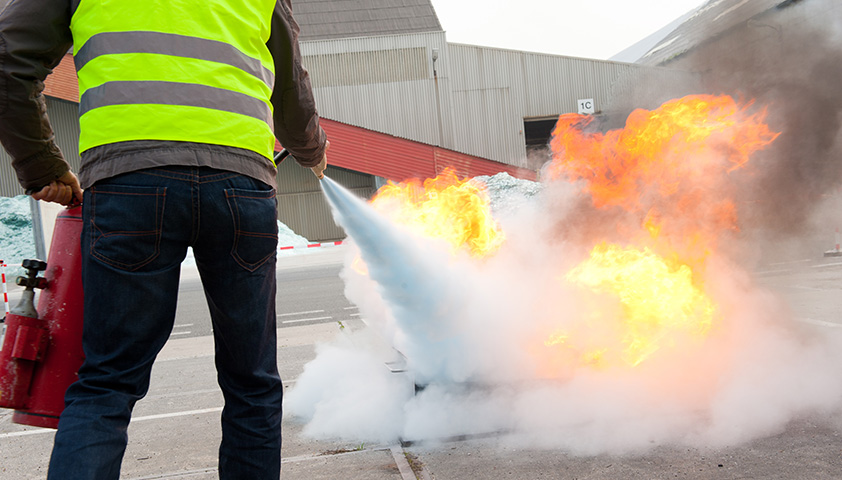 MORAVIA Akademie Aktuell: Brandschutzhelfer: Gefahren erkennen und minimieren & Baumpflege im Rahmen der Verkehrssicherungspflicht Ein Brandschutzhelfer löscht eine Flamme mit einem Feuerlöscher.