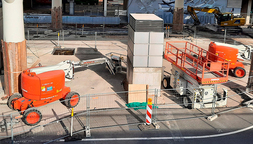 Baustellenfahrzeuge inklusive Hubarbeitsbühnen arbeiten am Bau eines neuen Gebäudes.
