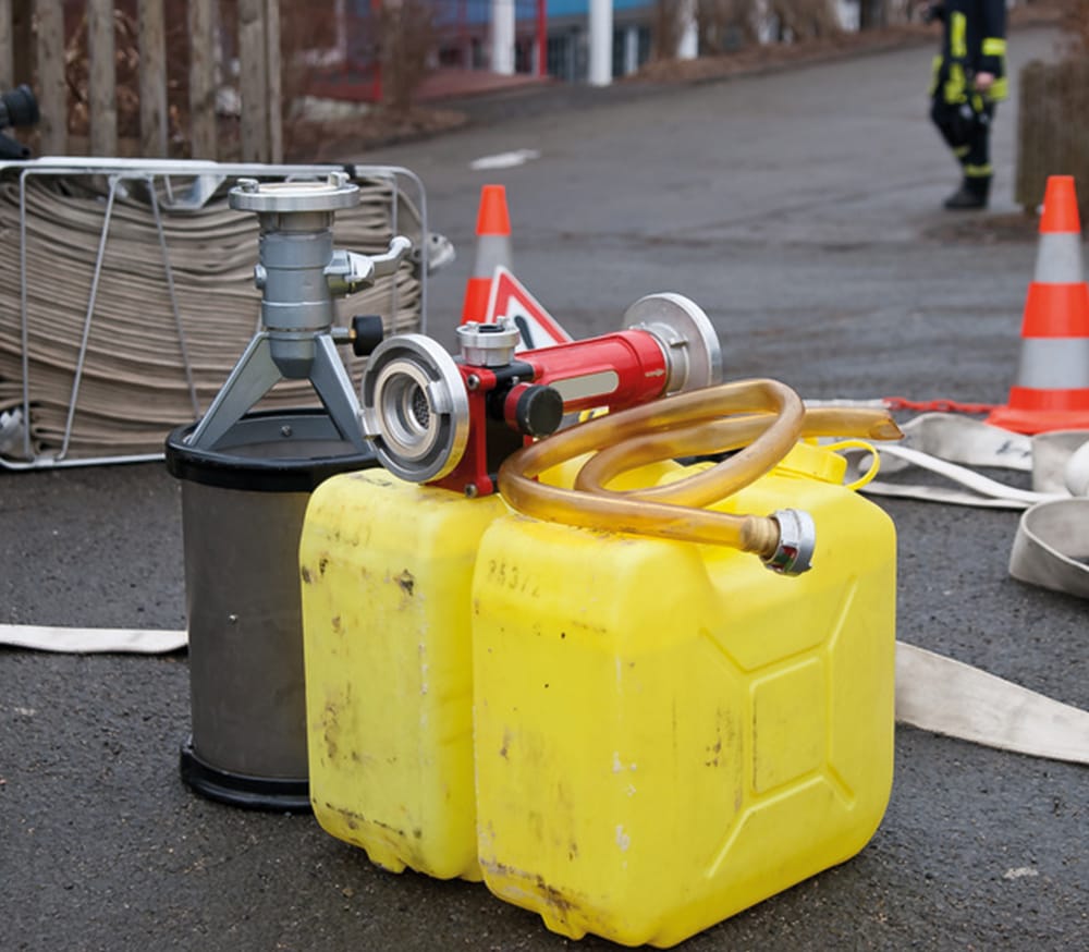 Schulung von Beauftragten Personen gem. Kapitel 1.3 ADR Gelbe und schwarze Container und Schläuche auf asphaltierter Staße.