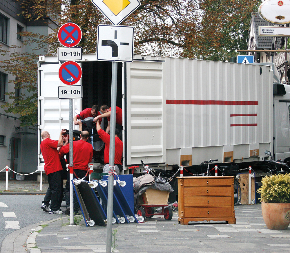 Schulung "Sicherung von Arbeitsstellen an Straßen für Möbelspeditionen" Umzugswagen wird von Gruppe beladen, weitere Möbel stehen daneben.