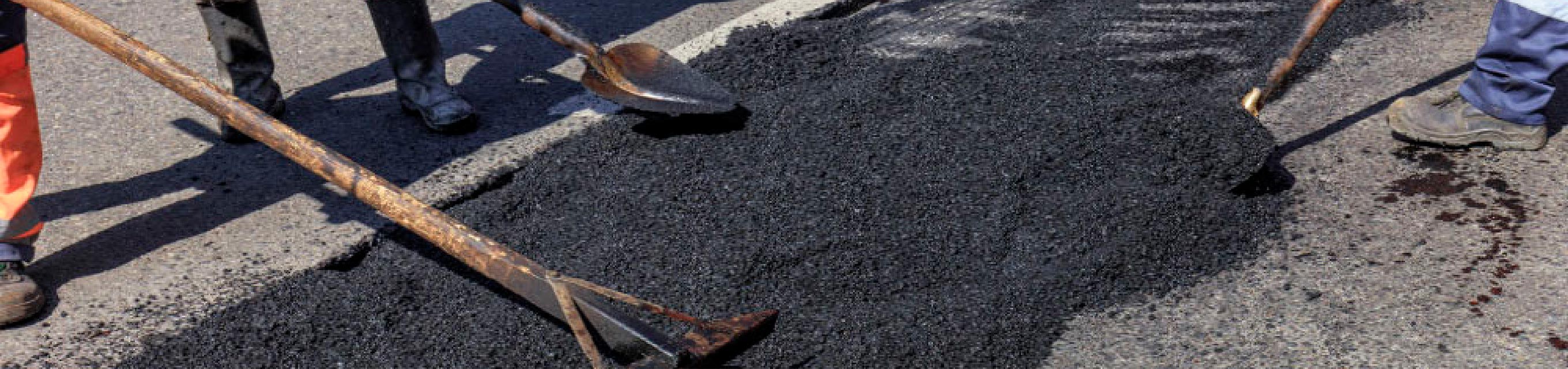 Asphalt wird auf die Straße aufgetragen und verarbeitet