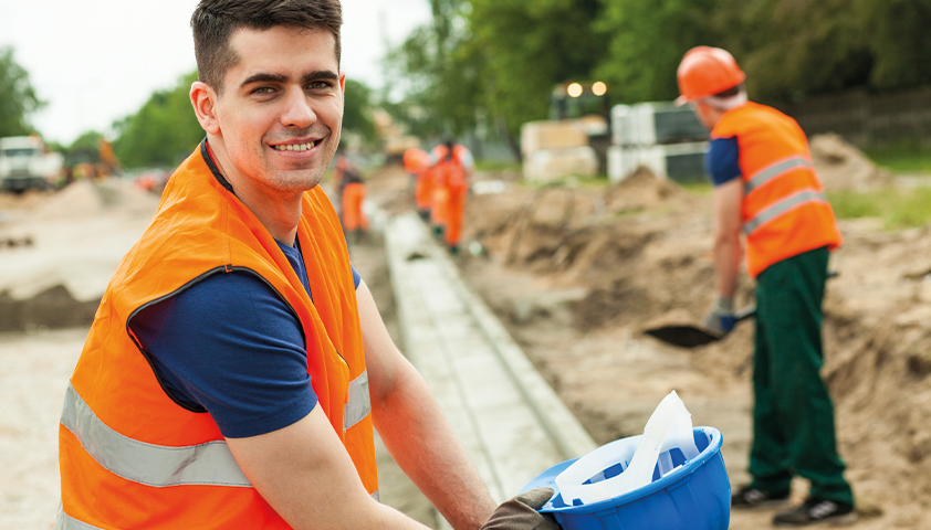 Mann auf Baustelle lächelt in die Kamera 