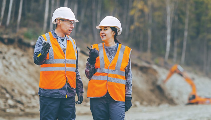 Zwei Arbeiter in Warnweste auf einer Baustelle besprechen sich